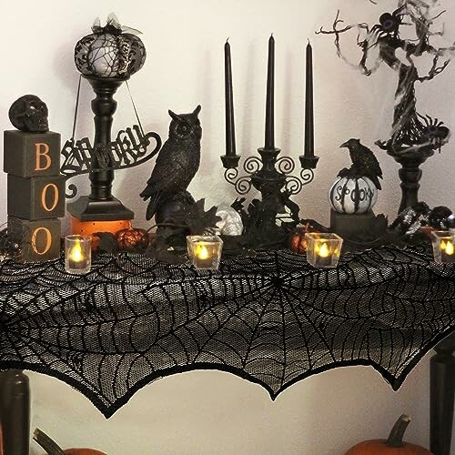 Halloween-themed table with candles, spider web cloth, and spooky decorations.