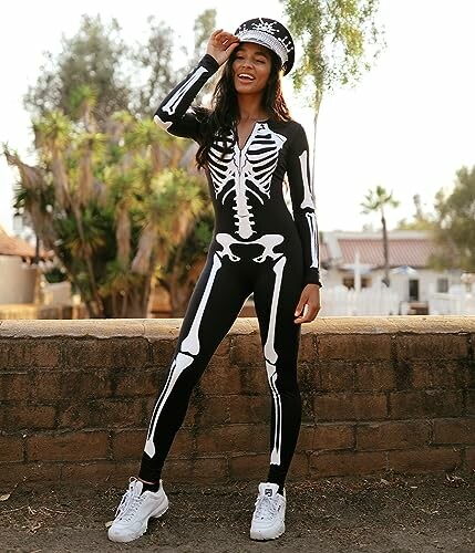 Woman in skeleton costume standing outdoors with a cap.